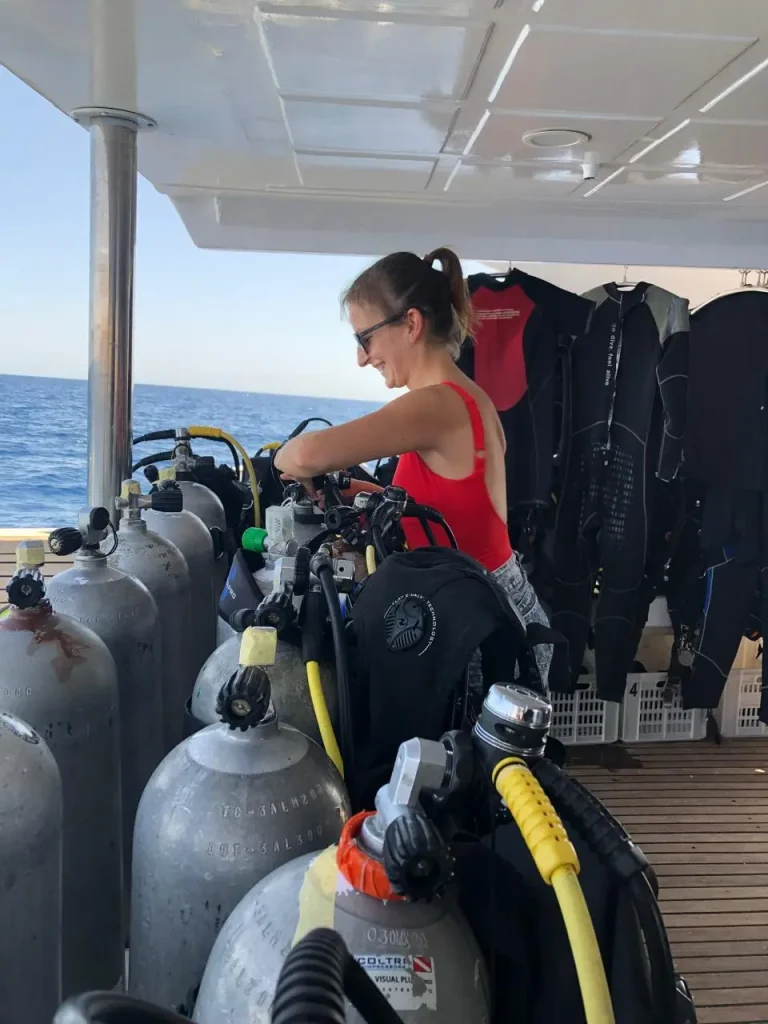 Uśmiechnięta dziewczyna montująca sprzęt nurkowy na naszej łodzi podczas kursu Open Water Diver PADI organizowany przez Wycieczki Hurghada