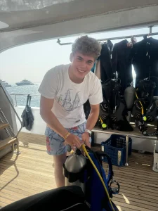 Uśmiechnięty chłopak montujący sprzęt nurkowy na naszej łodzi podczas kursu Open Water Diver PADI organizowany przez Wycieczki Hurghada