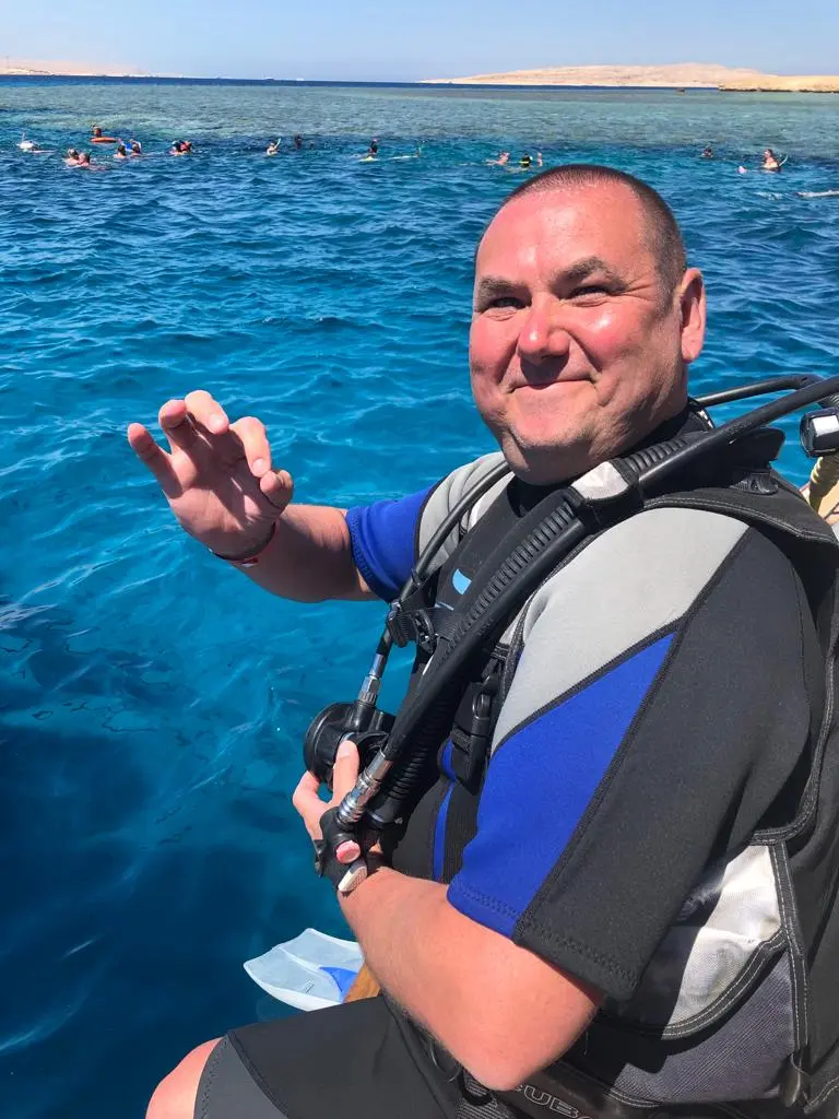 Uśmiechnięty mężczyzna gotowy do rozpoczęcia intro nurkowego z Wycieczki Hurghada